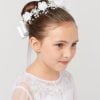 Girl wearing communion floral crown with white satin flowers, crystal accents, and ribbon back