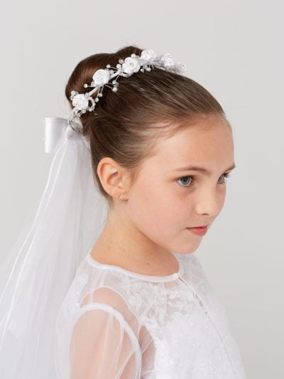 Girl wearing a white girls communion flower crown with veil.