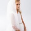 Girl wearing a girls communion veil scalloped with elegant layered design.