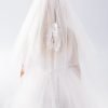 Girl wearing a girls communion veil virgin mary embroidered on the back.
